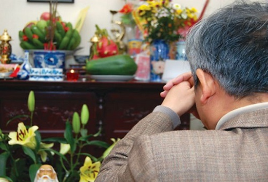 Một người đàn ông đang đọc văn khấn Thổ công và gia tiên khi về nhà mới mạch lạc